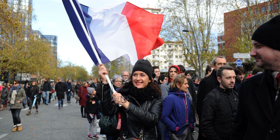A woman waves a French flag as people take part in a silent walk to s